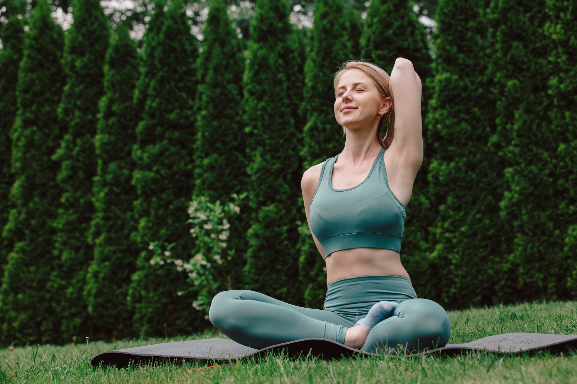 young woman practicing yoga on the grass in the garden